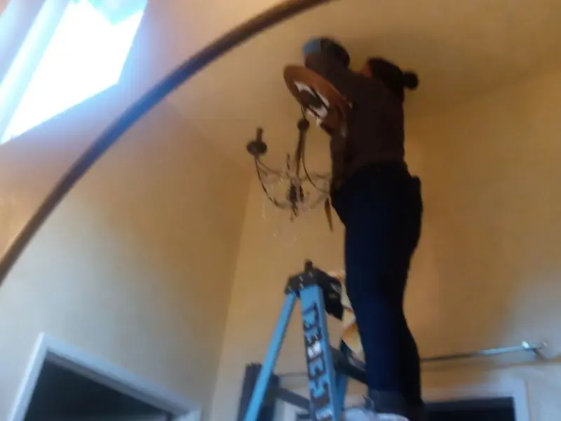 Electrician installing a chandelier in a North Ogden residence